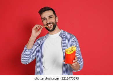 Man Eating French Fries On Red Background