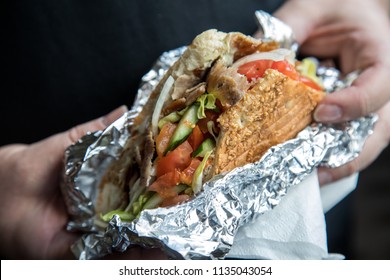 Man Eating German Döner Kebab In Pita Flatbread With Salad And Veal Meat Wrapped In Aluminium Foil 