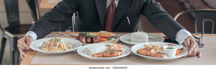 Man Eating Lots Of Food On The Table With Fired Fish, Pork Steak, Steam Cooking Rice, Health Care Concept.