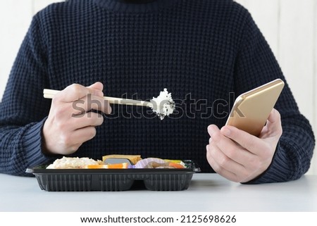 Man eating lunch while using smart phone