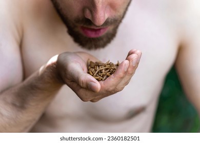 Man eating mealworms, concept of survivalism and alternative diet. Selective focus - Powered by Shutterstock