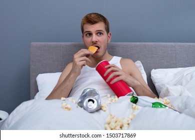 Man Eating In Messy Bed At Home