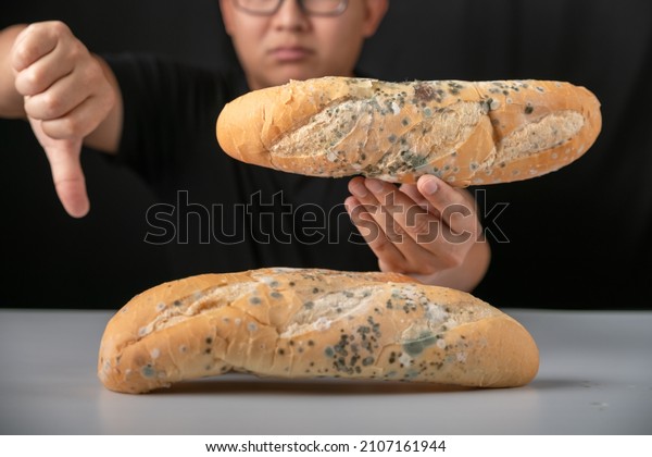 Man eating moldy dirty bread. man standing\
holding moldy bread. Moldy bread on blurry background. food fungus.\
Dirty food that is\
unappetizing.