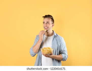 Man eating potato chips on color background