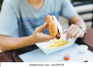 Man Is Eating In A Restaurant And Enjoying Delicious Hotdog Food