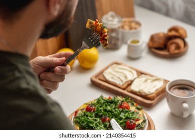 Man Eating Scrambled Eggs With Cherry Tomatoes And Parsley