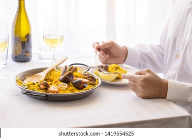 Man Eating Seafood Paella In Restaurant In Valencia, Spain. Typical Spanish Dish Lifestyle Image.