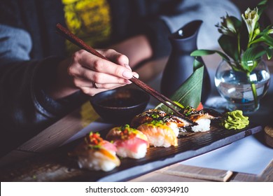 Man eating sushi set with chopsticks on restaurant - Powered by Shutterstock