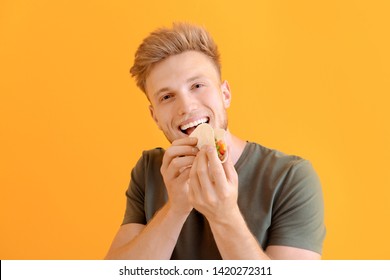 Man Eating Tasty Taco On Color Background