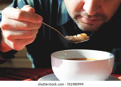 Man Eating White Bean Soup Sprinkled With Chilli Pepper In White Ceramic Bowl. Traditional Bulgarian Dish.