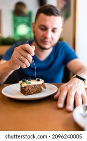 A Man Eats A Cake With Blueberries In A Cafe. Front View.