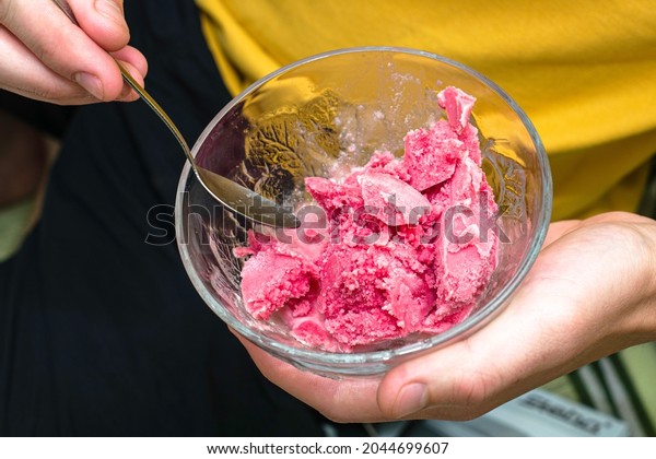 a man eats cherry ice cream with a\
spoon from an ice cream maker. High quality\
photo