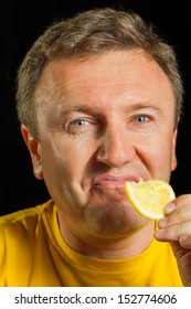 A man eats a lemon on a black background