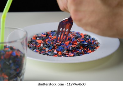 The Man Eats Pieces Of Crushed Recycled Plastic From White Plate.Food And Drink Contains Plastics. A Glass Full Of Recycled Plastic And A Plastic Pieces On White Plate.