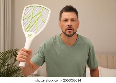 Man With Electric Fly Swatter In Bedroom. Insect Killer