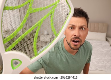 Man With Electric Fly Swatter In Bedroom. Insect Killer