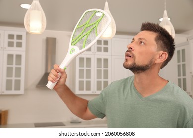 Man With Electric Fly Swatter In Kitchen. Insect Killer