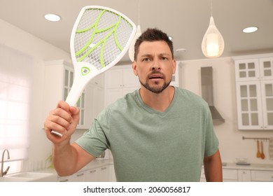 Man With Electric Fly Swatter In Kitchen. Insect Killer