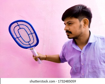 Man With Electric Mosquito Kill Racket, Bug Zapper, On Pink Background. Selective Focus.