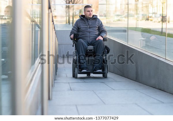 Man in a electric\
wheelchair using a ramp