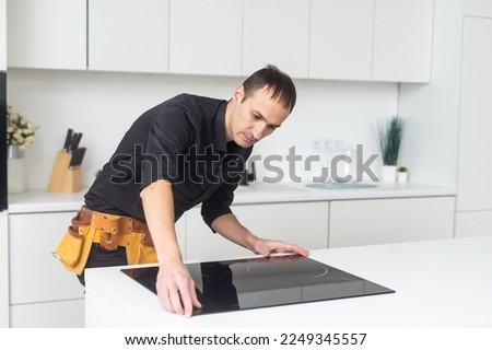 Man electrical repairs kitchen surface apartment. Installing hob in countertop. Man bought new kitchen furniture and appliances. Process installing an electrician household appliances.