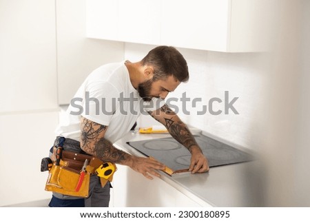 Man electrical repairs kitchen surface apartment. Installing hob in countertop. Man bought new kitchen furniture and appliances. Process installing an electrician household appliances.