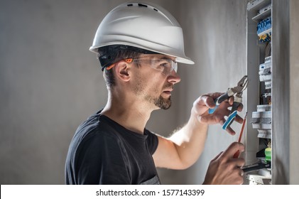 Man, an electrical technician working in a switchboard with fuses. Installation and connection of electrical equipment. Professional with tools in hand. concept of complex work, space for text.