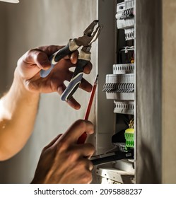 Man, an electrical technician working in a switchboard with fuses. Installation and connection of electrical equipment. Professional with tools in hand. concept of complex work, space for text. - Shutterstock ID 2095888237