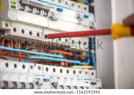 Man, an electrical technician working in a switchboard with fuses. Installation and connection of electrical equipment. Professional with tools in hand. concept of complex work, space for text.