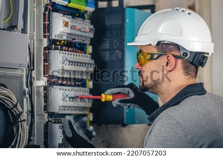 Man, an electrical technician working in a switchboard with fuses.