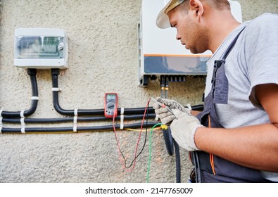 Man Electrician Installing Solar Panel System. Inspector In Gloves Making Electrical Wiring Inverter And Electric Box. Concept Of Alternative And Renewable Energy.