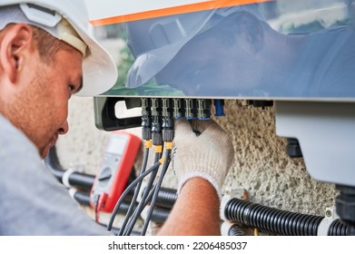 Man electrician installing solar panel system. Inspector in gloves making electrical wiring inverter and electric box. Concept of alternative and renewable energy.