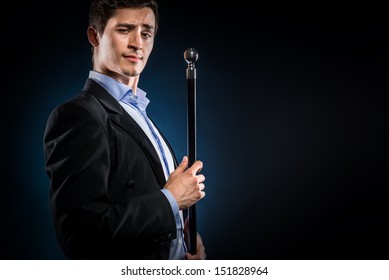 Man in elegant black jacket and blue shirt holding cane with silver ball handle