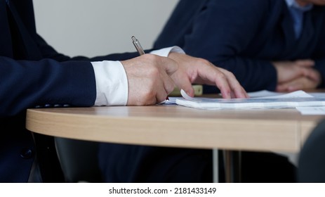 Man In An Elegant Suit Signs Or Endorses A Document During A Working Meeting Or Negotiations. No Face. Clerk, Official, Deputy, Politician, Lawyer Or Businessman. Selective Focus. Close-up