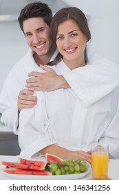 Man Embracing His Wife Who Is Wearing A Dressing Gown In The Kitchen