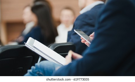 Man Employee In Suit Uses Digital Device Sitting On The Forum About Industry And Economy