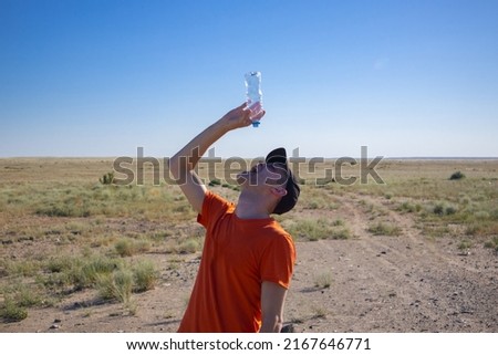 a man with an empty bottle in the desert. thirst. danger of dehydration. out of water