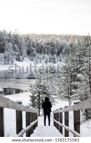 Man in the end of a snowy stairway. Forest and a lake located in Ogre, Latvia - on a snowy Winter day