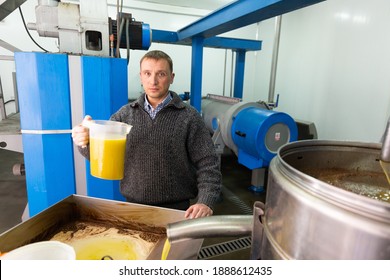 Man engaged in traditional olive oil production, controlling process of oil decanting - Powered by Shutterstock