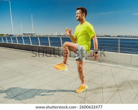 Man engaged in warm-up exercise along waterfront promenade on sunny day