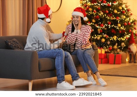 Man with engagement ring making proposal to his girlfriend at home on Christmas
