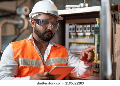 Man Engineer Wear Safety Vest With Helmet Safety Protection Holding Tablet Checking And Repairing Electrical Control Cabinet For Machines In Food And Beverage Factory Industry