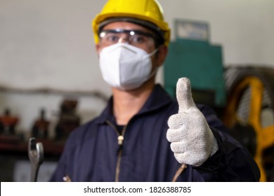 A Man (engineer) Wearing Helmet, Safety Glasses, And A Mask Holding Wrench And Showing His Thumb Up In The Metalworking Manufacturing Factory. Good Work In Workplace And Industrial Concept