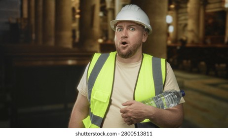 Man engineer in white hardhat and fluorescent vest holding water bottle in church building with mouth open and hand on bottle; surprise concern.