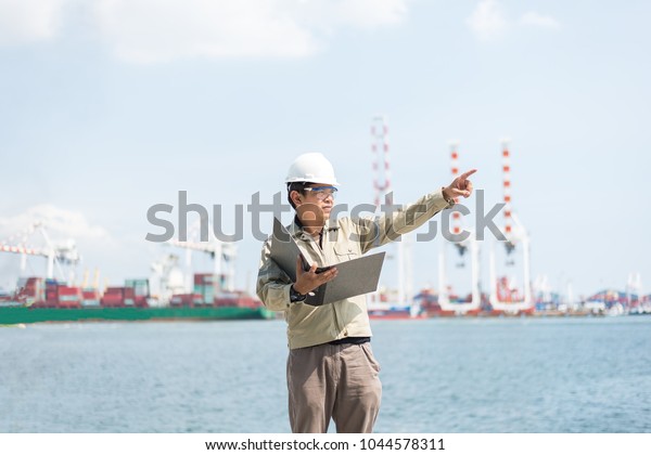 The man\
engineer working with container Cargo freight ship in shipyard at\
dusk for Logistic Import Export\
background\
