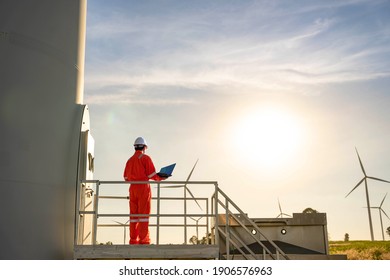 Man engineer working and holding the laptop for check performance of wind turbine farm Power Generator Station, Concept of sustainable resources, Concept of professional for the energy industry.