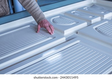 a man engineer working on a machine for sticking a film on an MDF panel close-up, the front and back background is blurred with a bokeh effect