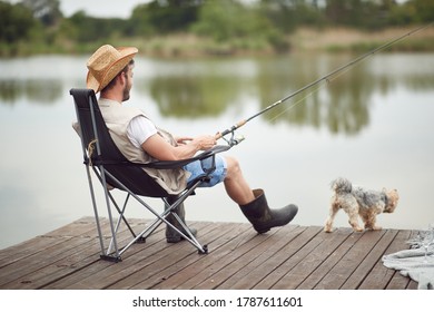 A man enjoying fishing on a dock with his dog  - Powered by Shutterstock