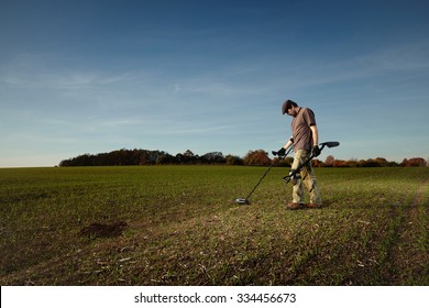 Man Enjoying Recreational Archeology With Metal Detector In Autumn Field