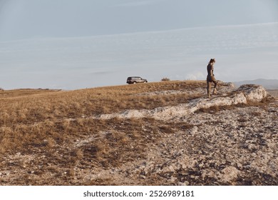 Man enjoying scenic view from hilltop with parked suv, travel adventure concept - Powered by Shutterstock